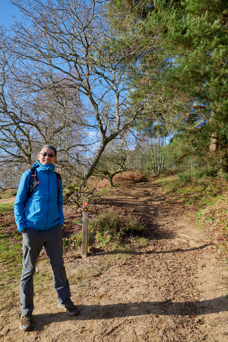 Ralph Wong, a conservation volunteer standing by a finger post in the woodlands