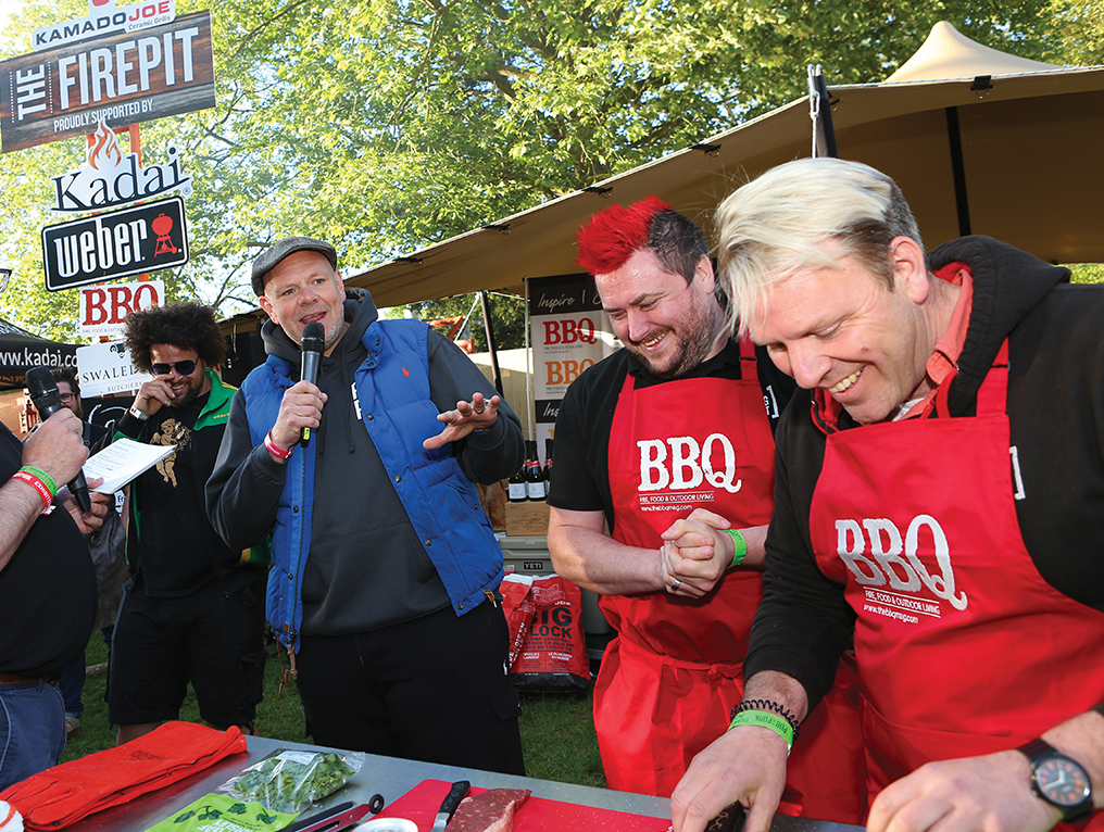 Two men in red aprons being interviewed by a man holding a microphone
