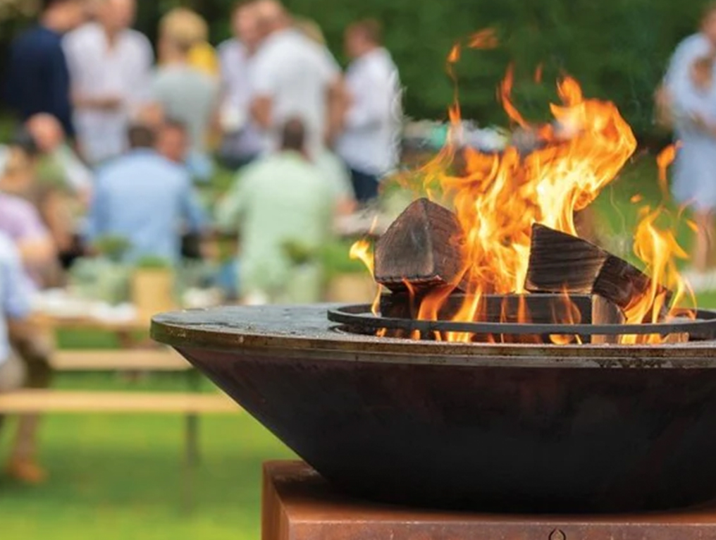 Fire pit with people in the background sitting at tables