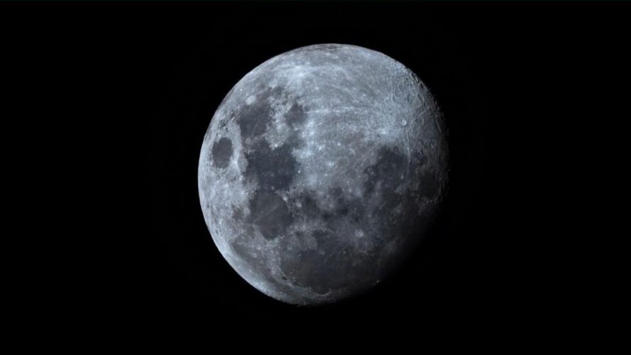 Close up image of a grey-looking moon against a dark sky.