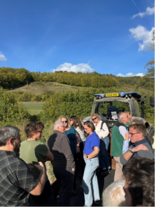 People standing behind a tractor looking at the farm - rolling green hills and blue sky